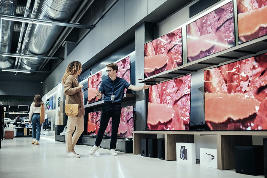 Electronics store employee helping a customer find the right television