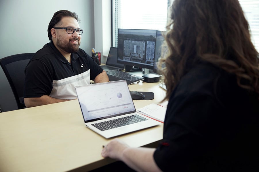 two people in office  with desktop and a laptop