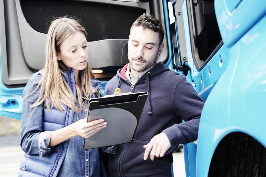 driver and shipping staff reviewing freight load bill of lading in front of open cab door